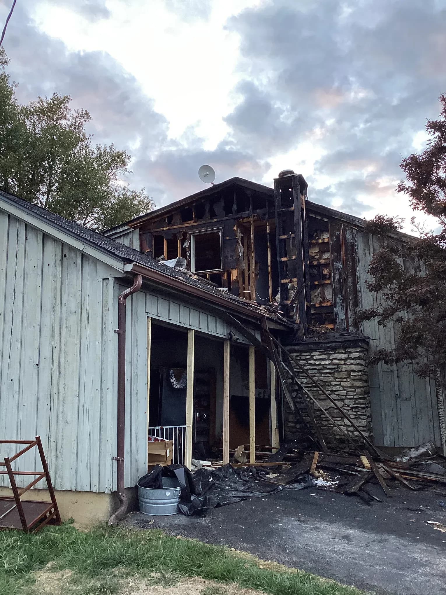 The outside of a house with its upper storey burned open and the siding scorched away
