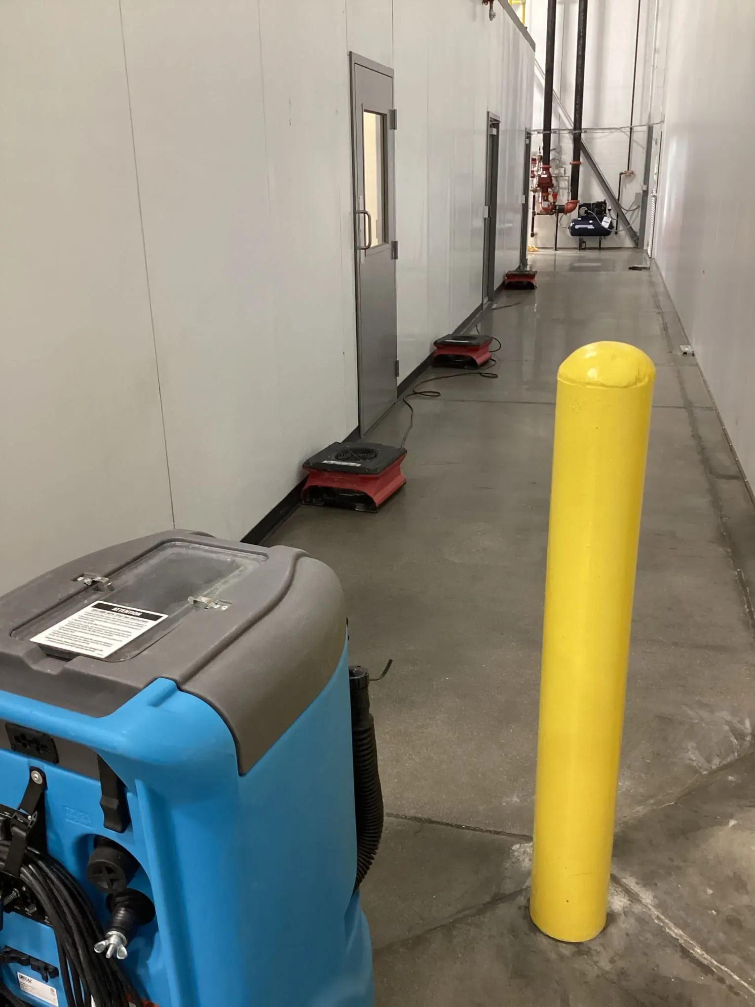 Commercial dehumidifier running on a wet floor during a drying job