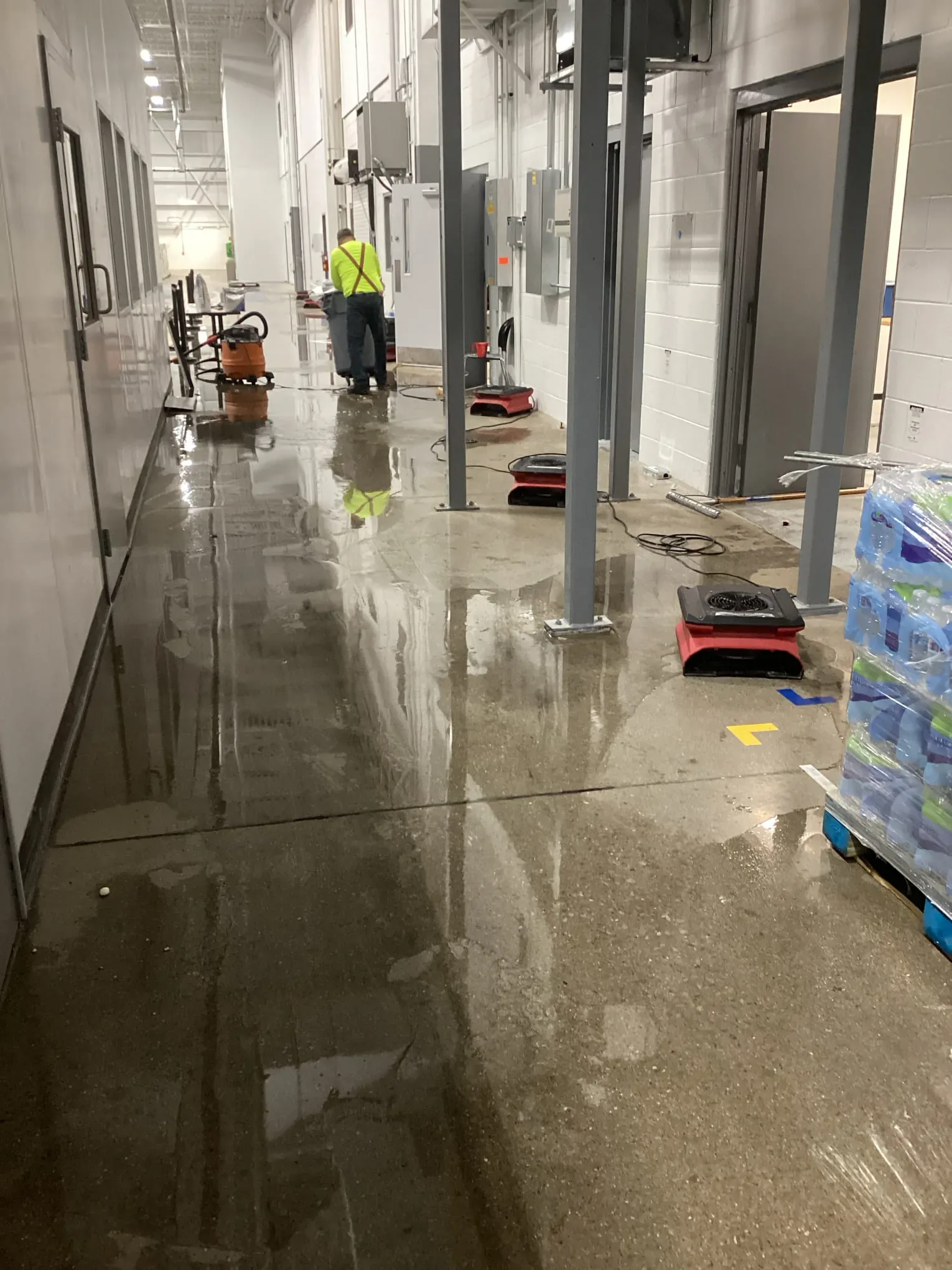 Technician working along a flooded hallway with extraction and drying equipment