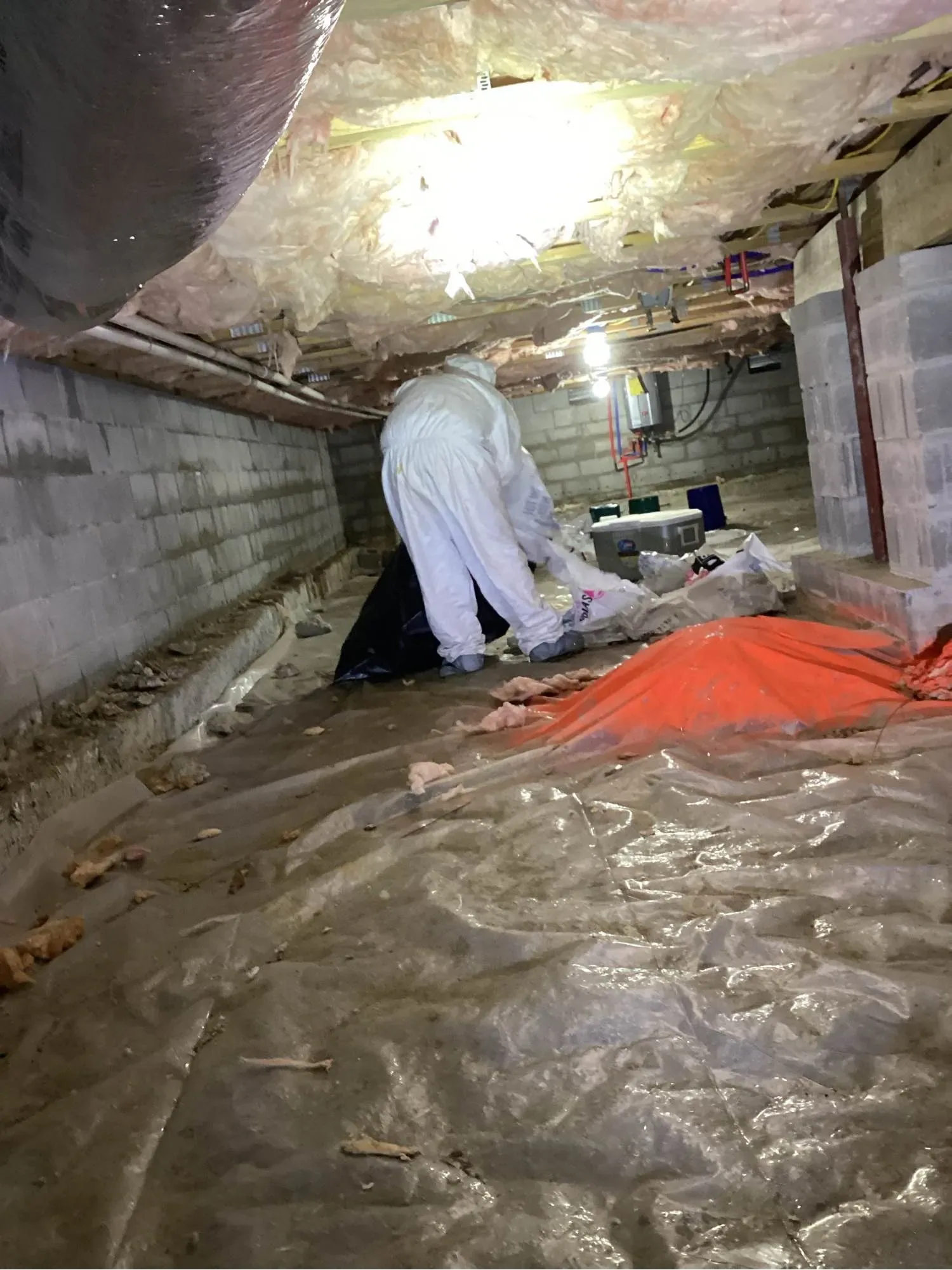 Technician working on a vapor barrier inside a crawl space
