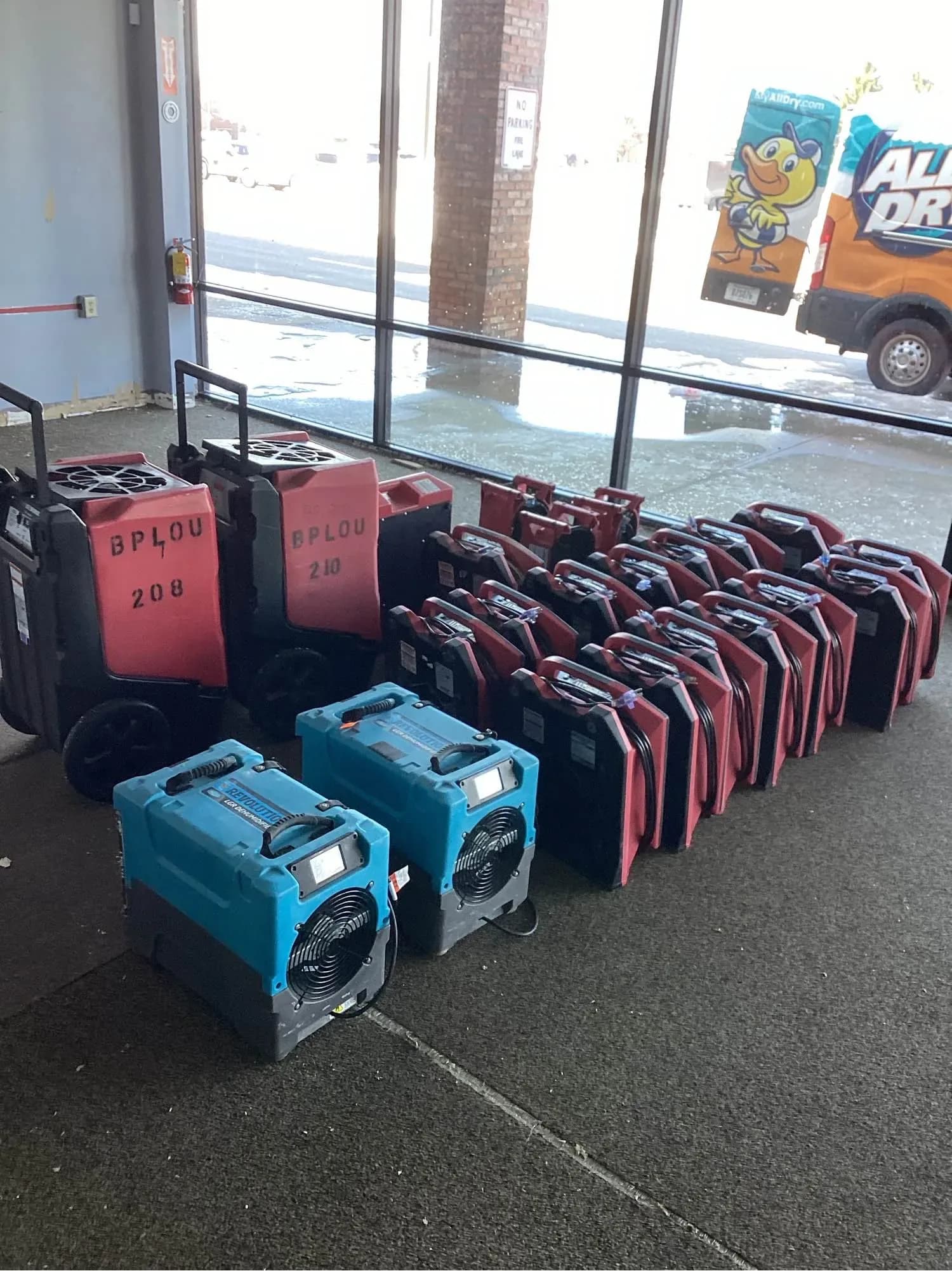 Commercial dehumidifiers and air movers staged inside a property with the van parked outside
