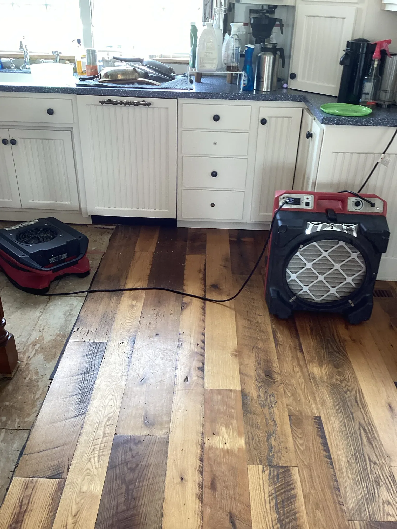 Commercial air mover drying a hardwood floor after water came in through the building envelope