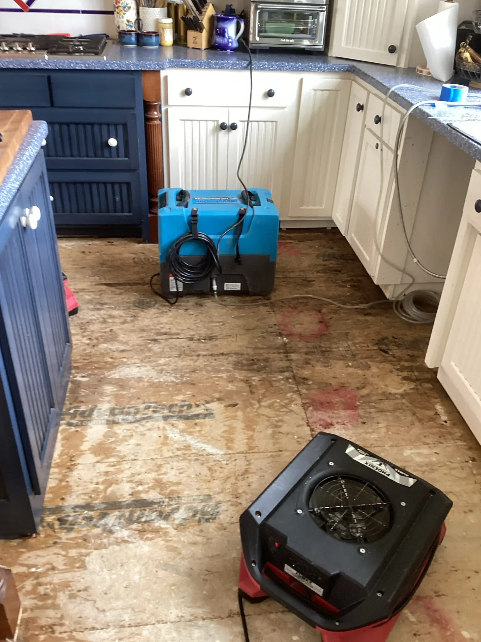 Kitchen stripped to the subfloor with a commercial dehumidifier and air mover drying it