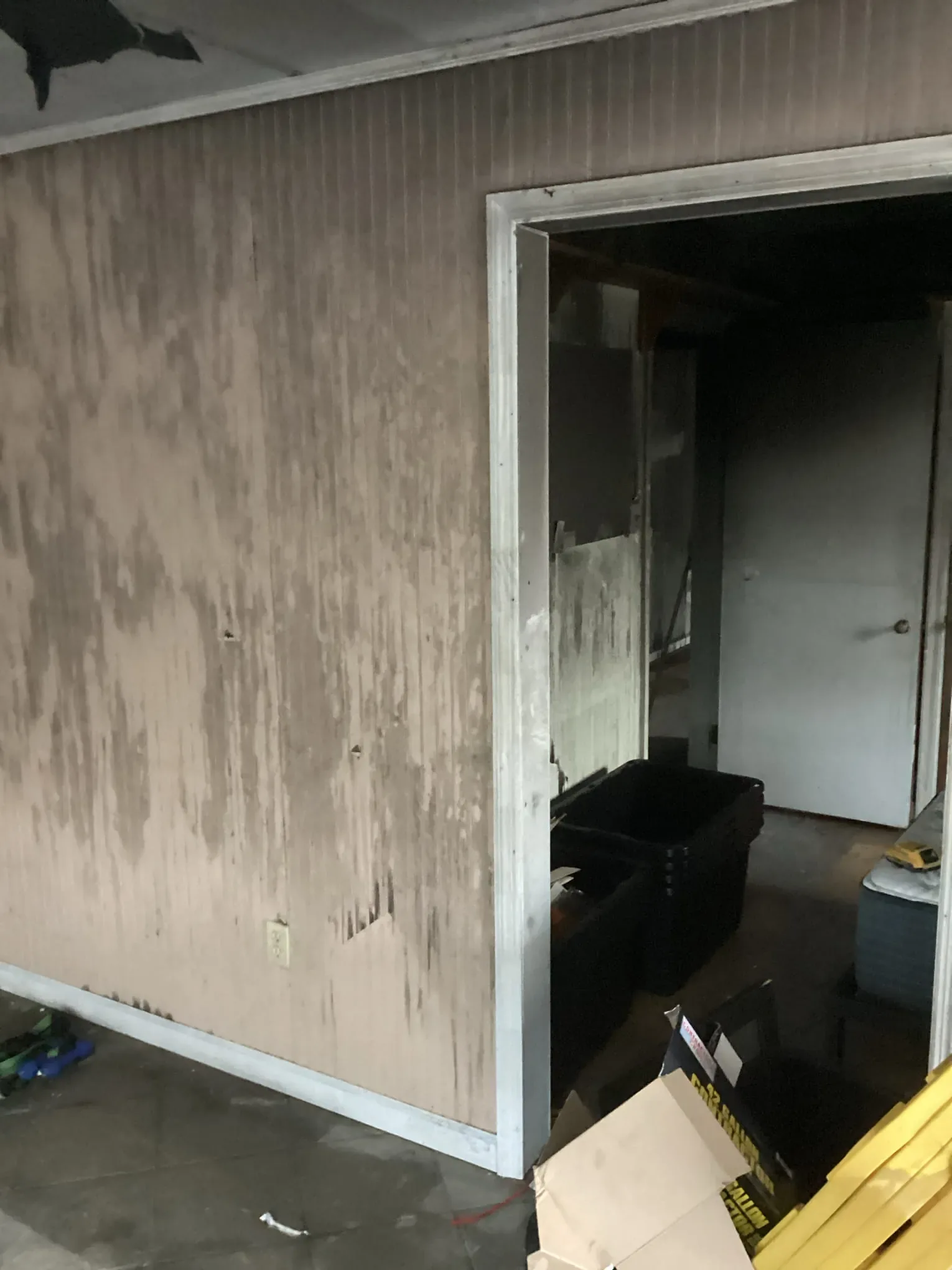 Room with soot darkened walls and a doorway leading through to a damaged space beyond