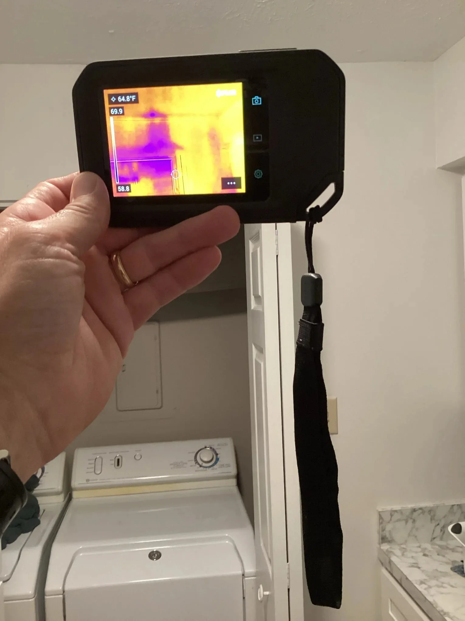 Technician scanning a wall with a thermal imaging camera during an inspection